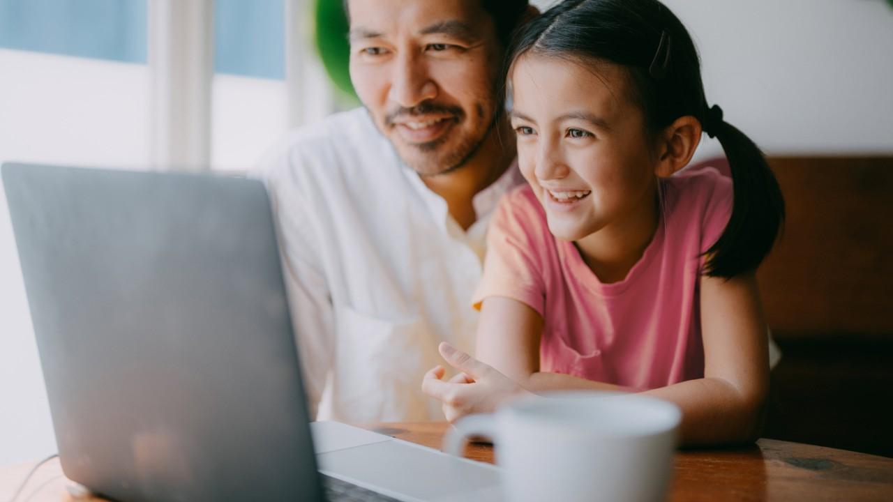 父亲和女儿在家里用笔记本电脑视频通话